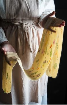 a person holding two bananas in their hands and wearing a yellow apron with designs on them