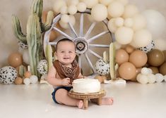 a baby sitting on the floor with a cake in front of him and balloons around him