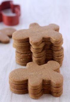 a stack of cookies sitting on top of a white table next to cookie cutters