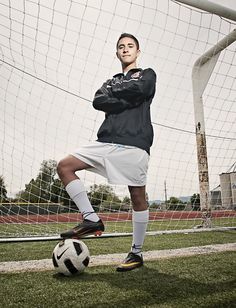 a man standing in front of a soccer ball on top of a grass covered field