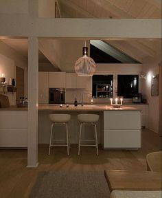 an open kitchen and living room area in a house with white walls, wood floors and ceiling beams