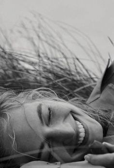 black and white photograph of a woman laying down with her hair blowing in the wind