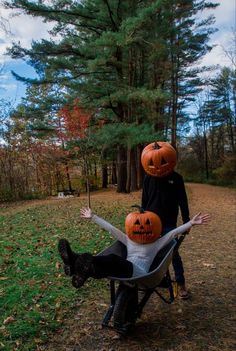 two people sitting in a chair with pumpkins on their heads