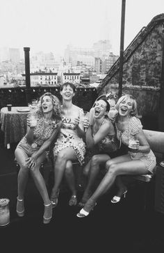 four women are sitting on a bench and laughing