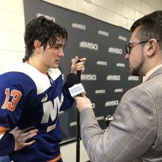 a man is interviewed by an announcer in front of a black wall with a sign