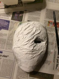 a paper mache sitting on top of a newspaper next to a marker and pen