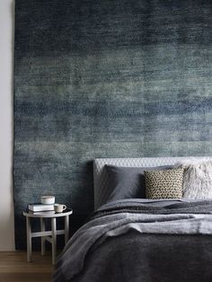 a bedroom with a large blue rug on the wall and a bed in front of it