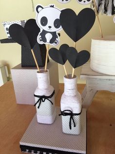 two vases with black and white paper cutouts in them on a wooden table