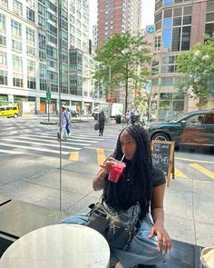 a woman sitting at an outdoor table with a drink in her hand