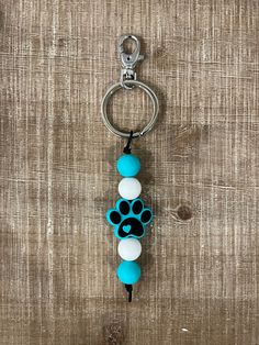 a key chain with a dog's paw print on it and two balls attached to it