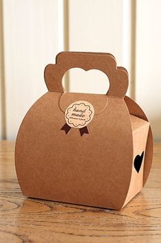 a small brown box with a bow on the front and handle is sitting on a wooden table