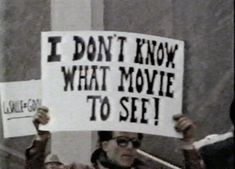 a woman holding up a sign that says i don't know what movie to see