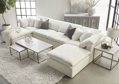 a living room with white couches and pillows on the floor next to a coffee table