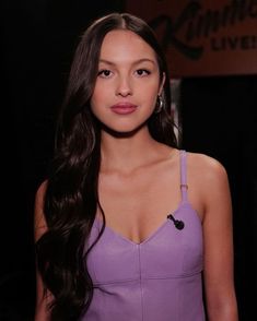 a woman with long dark hair wearing a purple dress