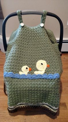 a crocheted baby blanket with two ducks on it sitting in a stroller