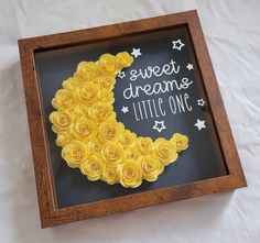 there is a shadow box that has yellow roses in the shape of a moon on it