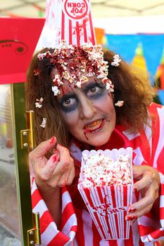 a woman with makeup on holding a popcorn box