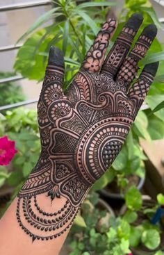 a hand with henna on it in front of some plants and potted plants