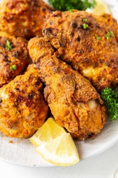 three fried chicken patties on a plate with lemon wedges and garnished parsley