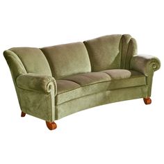 a green velvet couch with wooden legs and arm rests on an isolated white background,