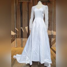 a white wedding dress on display in front of a wooden wall