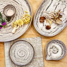 three plates with different designs and flowers on top of each plate, sitting on a wooden table