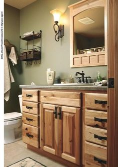 a bathroom with wooden cabinets and a white toilet next to a wall mounted light fixture