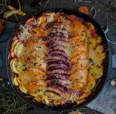 an oval casserole dish with cheese and vegetables