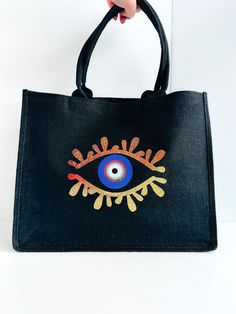 a hand holding a black bag with an eye painted on it