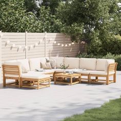 an outdoor seating area with wooden furniture and string lights on the wall behind it, surrounded by greenery