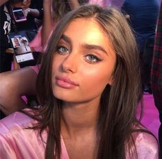 a beautiful young woman sitting in front of a camera taking a selfie with her cell phone