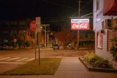 an empty street at night with a coca - cola sign