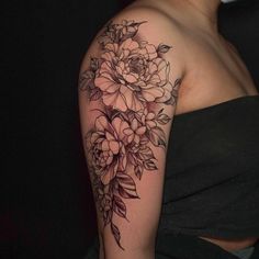 a woman's arm with flowers and leaves tattooed on her shoulder, in black and white