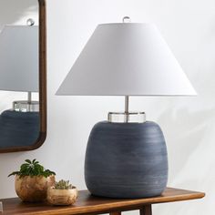 a blue vase sitting on top of a wooden table next to a mirror and lamp