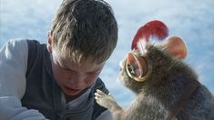 a young boy is petting a small animal in the air with its mouth open