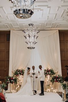 a bride and groom standing in front of the alter at their wedding ceremony with candles lit