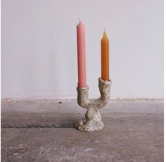 two candles sitting on top of each other in a room next to a white wall