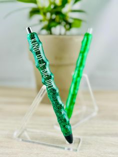 two green pens sitting next to each other on a wooden table near a potted plant