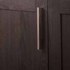 a close up of a door handle on a brown cabinet with wood grained doors