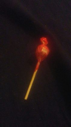 a red lollipop sitting on top of a black surface