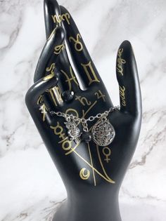 a black hand with gold writing and two rings on it's fingers is shown in front of a marble background