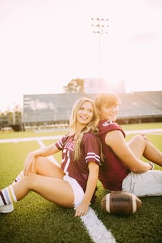 a man and woman sitting on the ground with a football in front of their backs