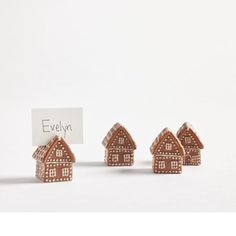 three tiny wooden houses are next to a sign