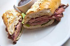 a cut in half sandwich sitting on top of a white plate next to a cup