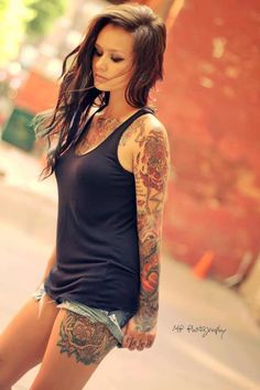 a woman with tattoos standing on the street