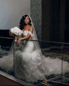 a woman in a wedding dress is holding flowers and posing for a photo on a balcony