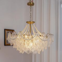 a chandelier hanging from the ceiling in a room with white walls and curtains