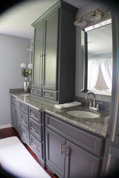 a bathroom with gray cabinets and marble counter tops