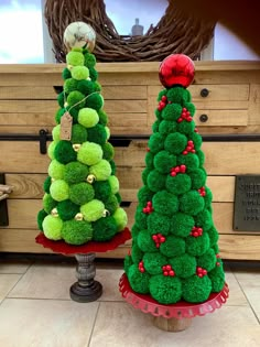 two green christmas trees sitting on top of red trays