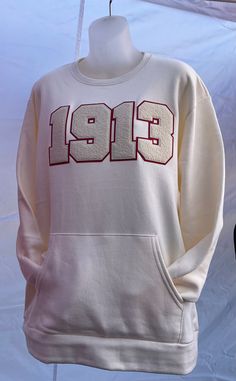 THIS IS A CUSTOM ITEM AND SHIIPING MAYBE DELAYED. A sturdy and warm DST Cream sweatshirt with chenille 1913. Sweatshirt with front pockets. A pre-shrunk, classic fit sweatshirt with a pocket in the front that's made with air-jet spun yarn for a soft feel and reduced pilling. • 50% cotton, 50% polyester• Pre-shrunk• Classic fit with no center crease• 1x1 athletic rib knit collar with spandex• Air-jet spun yarn with a soft feel and reduced pilling• Double-needle stitched collar, shoulders, armhole Cream Sporty Sweatshirt With Pockets, Sporty Cream Sweatshirt With Pockets, Sports Crew Neck Sweatshirt With Kangaroo Pocket, College Long Sleeve Sweatshirt With Kangaroo Pocket, Long Sleeve College Sweatshirt With Kangaroo Pocket, Sporty Crew Neck Sweater With Kangaroo Pocket, Sporty Cream Crew Sweatshirt, Sporty Cream Crew Neck Sweatshirt, Vintage Fleece Hoodie With Crew Neck